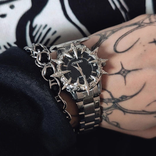 Close-up of a wrist wearing a silver watch with a black face, against a dark background.