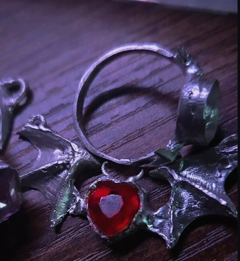 Silver pendant with a red gemstone on a wooden surface
