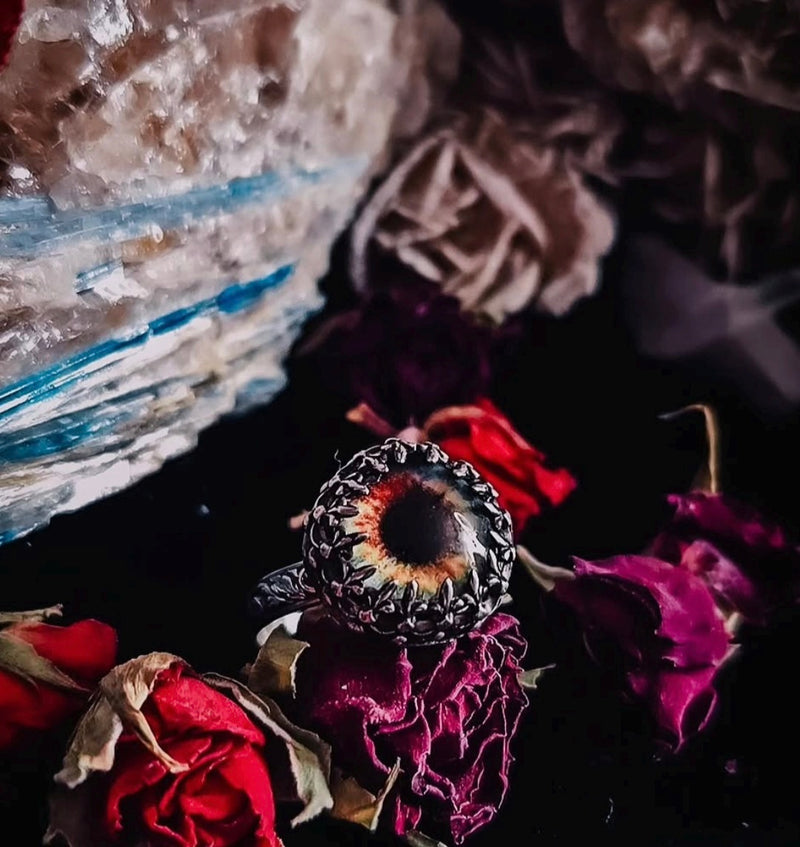 Ring with a dark stone on dried flowers and crystals