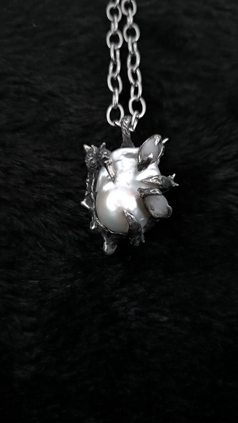 Silver pendant with a large pearl on a dark textured background moonstone dragon claw 