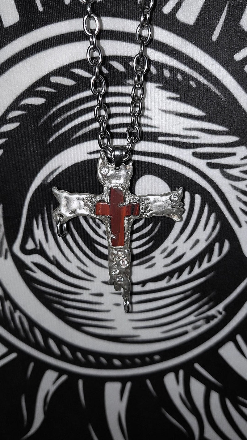 Cross pendant necklace with red center on a black and white abstract background