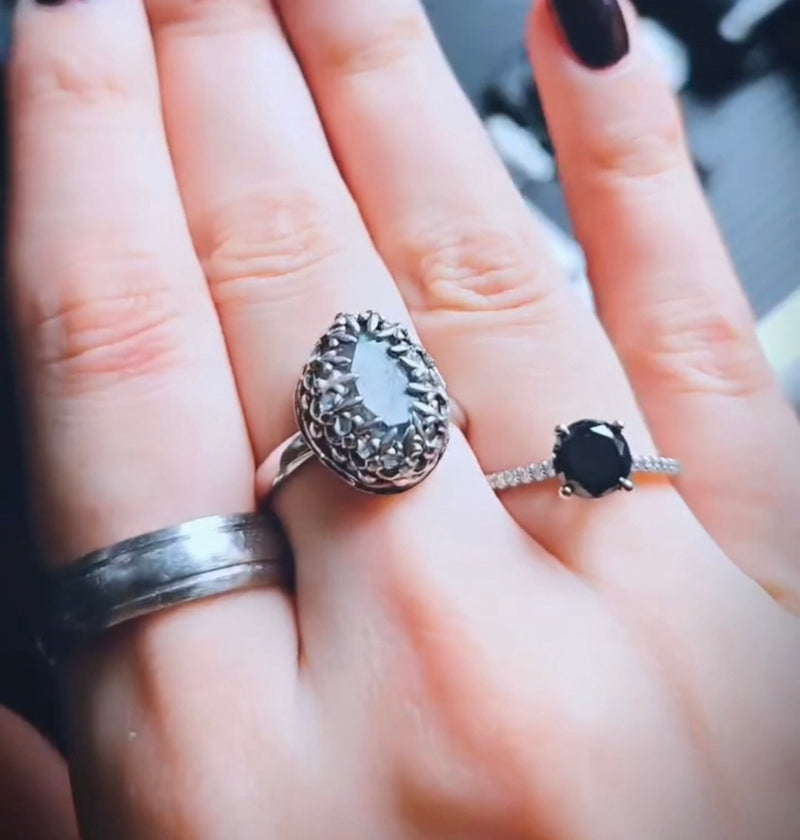 Close-up of a hand wearing three rings with intricate designs.