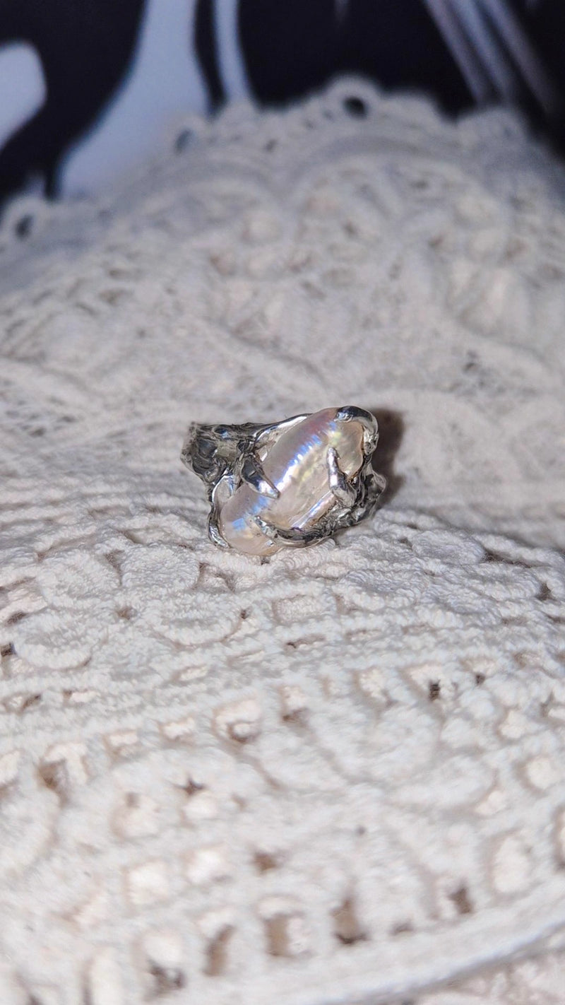 Silver ring with a large pearl on a textured surface