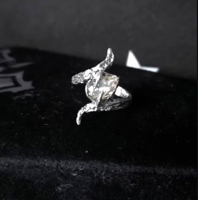 Silver ring with a diamond on a dark surface